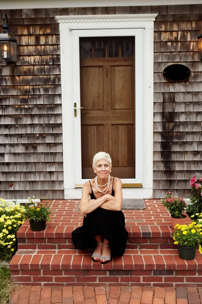 Portrait of a senior woman sitting at the front stoop of house