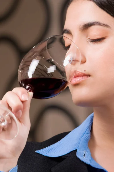 一位年轻女子在餐馆的背景下喝了一杯红酒 涂了红色口红 — 图库照片