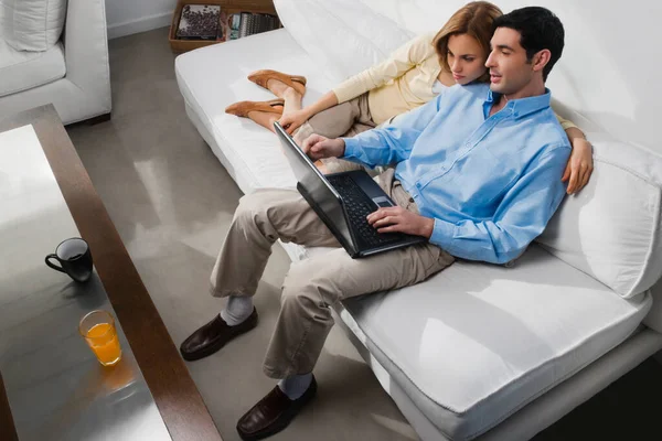 Jovem Casal Sentado Sofá Usando Laptop Enquanto Deitado Chão Casa — Fotografia de Stock