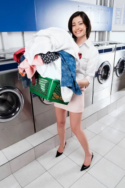 young woman with laundry and washing machine at home