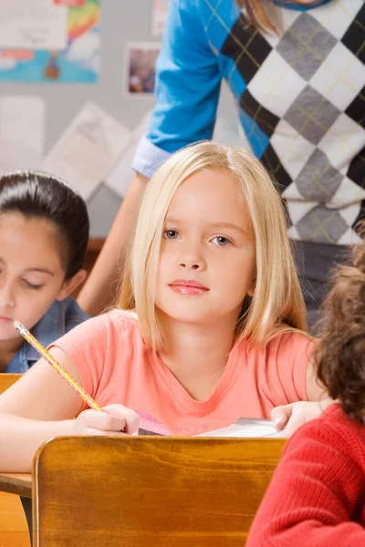 教室のテーブルに座っている笑顔の女子高生の肖像画です — ストック写真