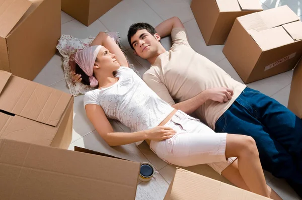 若い夫婦が床に横になって新しい家を見て — ストック写真