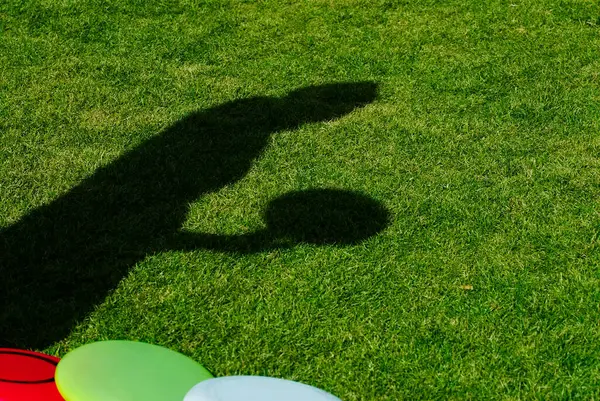 High angle view of a shadow of a person holding a plastic disc