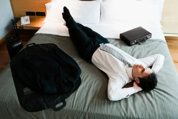 彼の頭の後ろに彼の手でベッドの上で休んでビジネスマンの高い角度のビュー — ストック写真