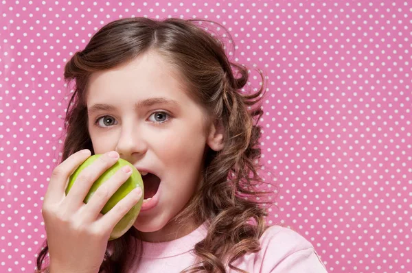 ピンクの背景に新鮮な果物を食べる巻き毛の美しい女の子 — ストック写真