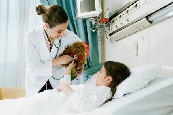 Flicka Sjukhussäng Med Kvinnlig Läkare Undersöker Uppstoppad Leksak — Stockfoto