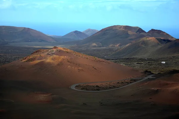 Timanfaya国家公园五彩斑斓的火山景观 西班牙加那利群岛兰萨罗特岛 穿过国家公园的路右手边有一辆白色巴士 — 图库照片