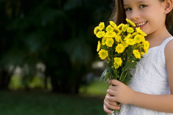 庭に花の花束を持つ美しい少女 — ストック写真