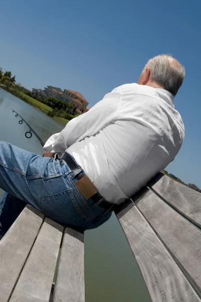 ベンチに座って海を見ている男は — ストック写真