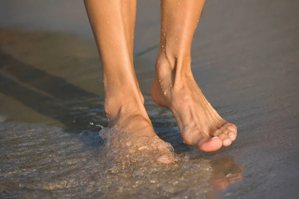 女人的脚在海滩上的水里 — 图库照片