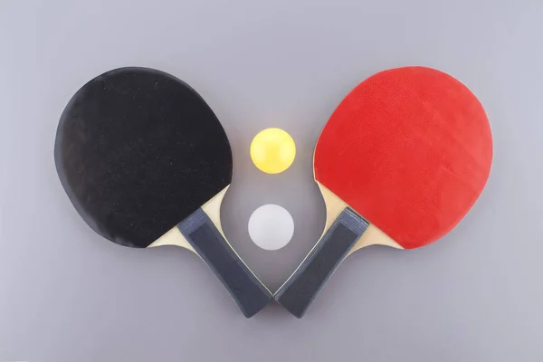 グレーを背景に白と黄色のピンポンボールと赤と黒の卓球ラック — ストック写真