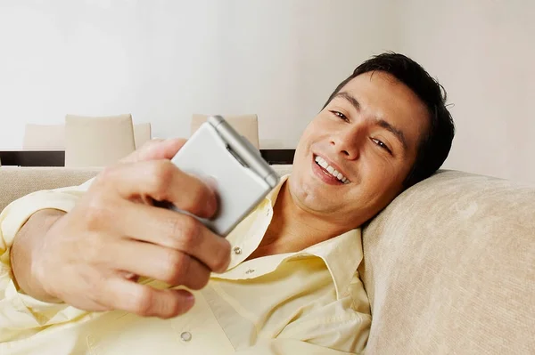 Junger Mann Liegt Auf Sofa Und Benutzt Handy — Stockfoto