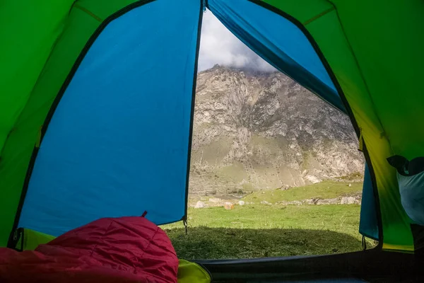 緑の草を背景にバックパックとキャンプ用テントがあるテントは — ストック写真