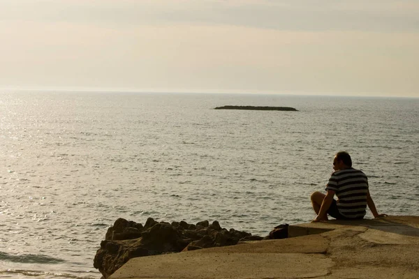 Uomo Seduto Sulla Spiaggia Con Uno Zaino Cappello Sul Mare — Foto Stock