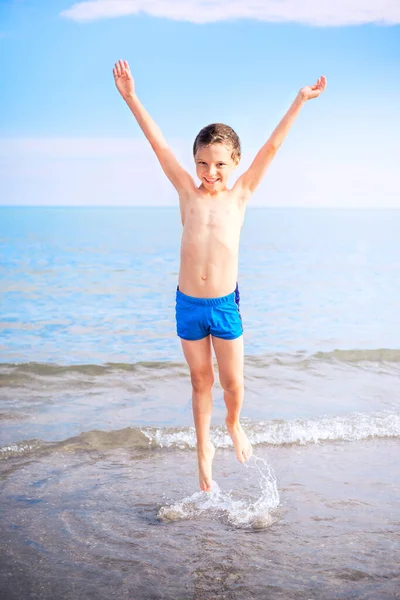ビーチで遊んでいる青い水着の幸せな男の子 — ストック写真