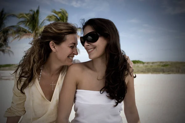 两个戴着太阳镜的年轻女子和她在海滩上的男朋友的画像 — 图库照片