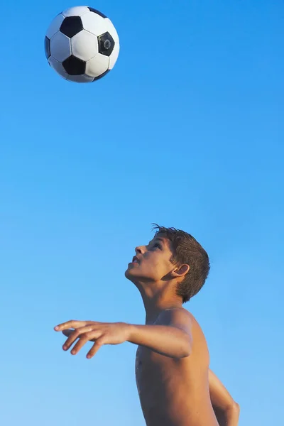 Αγόρι Που Παίζει Μπάλα Ποδοσφαίρου Ενάντια Στον Γαλάζιο Ουρανό — Φωτογραφία Αρχείου