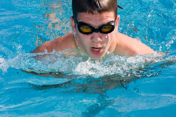 戴着太阳镜的年轻人在游泳池里游泳 — 图库照片