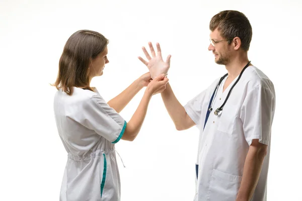 看護師はゴム滅菌手袋を着用する医師を助けます — ストック写真