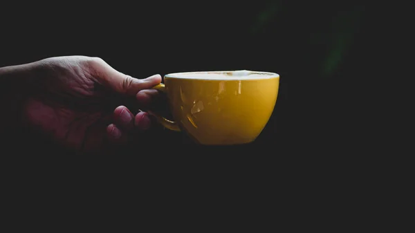 Tutup Tangan Terisolasi Memegang Mug Kuning Pada Latar Belakang Hitam — Stok Foto