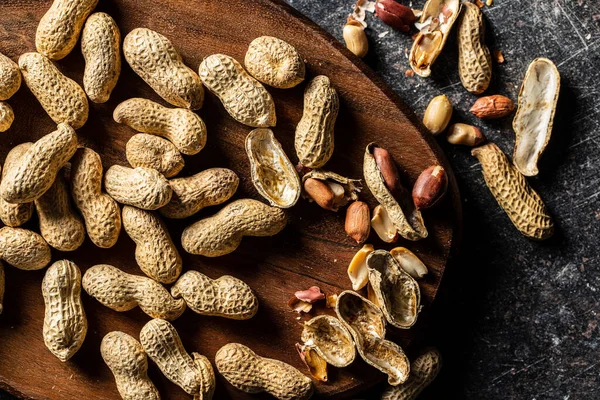 Roasted peanuts. Tasty groundnuts on cutting board. Top view.