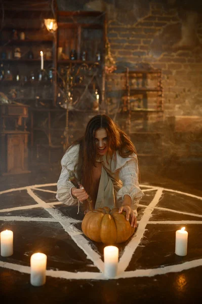 一个疯狂的魔女 拿着南瓜坐在魔法圈里 拿着蜡烛 恶魔把她赶出去 神秘超自然的仪式 黑暗的宗教 夜间恐怖 背景中的药水 — 图库照片