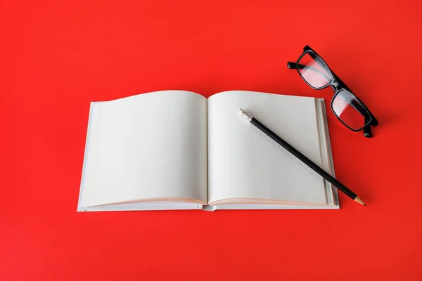 Foto Libro Blanco Lápiz Vasos Sobre Papel Rojo Una Maqueta — Foto de Stock