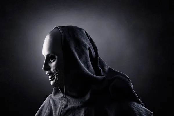 portrait of a scary vampire with a hood on a black background