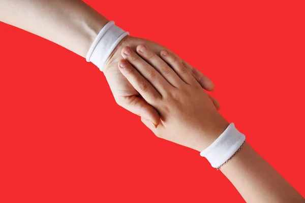 Helping Hands Concept Female Hands White Bracelets Red Backgroung — Stock Photo, Image
