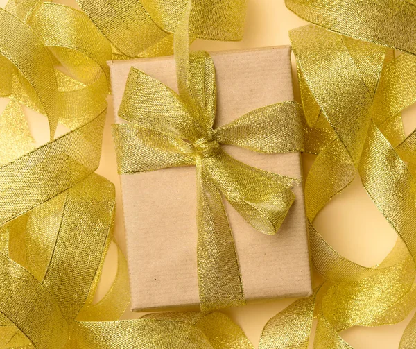 Geschenk Verpakt Bruin Papier Een Gedraaide Gouden Lint Achtergrond Feestelijke — Stockfoto