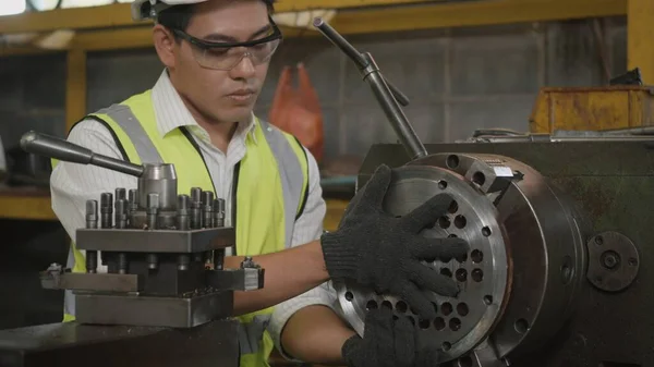 均一な硬さとゴーグルの安全労働者を身に着けているアジアの専門的な機械操作の男は ワークショップ金属旋盤工業生産工場 重工業でボルトを締めしています — ストック写真