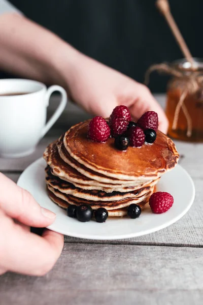 Las Manos Sostienen Plato Blanco Con Panqueques Bayas Miel Taza — Foto de Stock