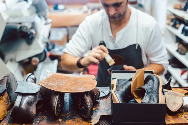 Shoemaker putting glue on sole of a shoe to fix