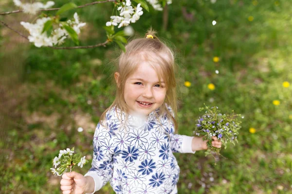 庭の緑の芝生の上に春の花を持つ少女 高品質の写真 — ストック写真