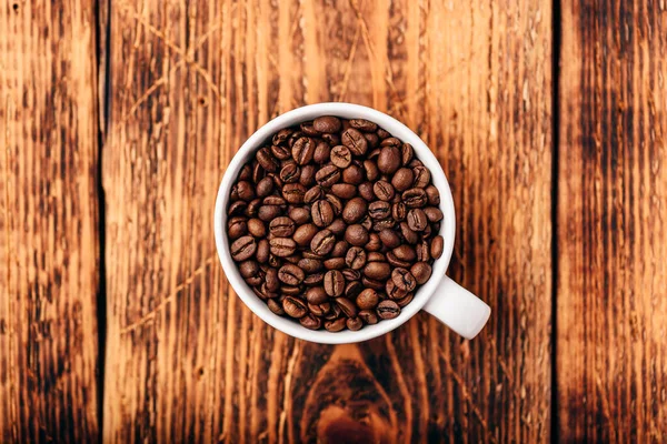 木製の表面の上にカップで焙煎コーヒー豆 — ストック写真