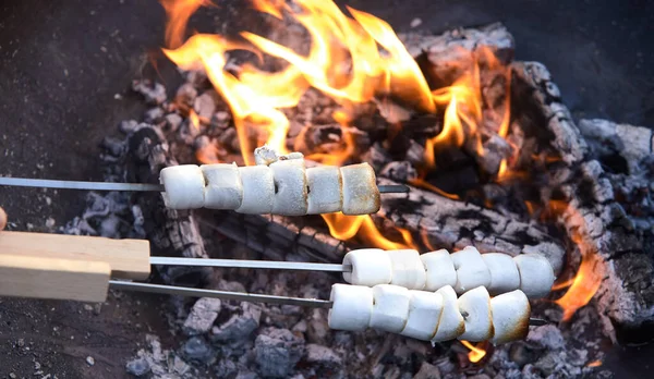 在夏季野餐期间 人们在篝火的炽热的煤块上烤着三根白色棉花糖 近距离观察糖果 — 图库照片