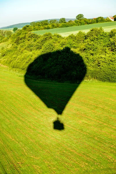 上空からの緑の風景の中の熱気球の影 — ストック写真