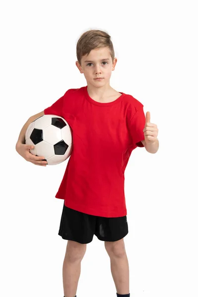 穿着红衫的男孩 脚上有足球和大拇指 背景是白色的 — 图库照片
