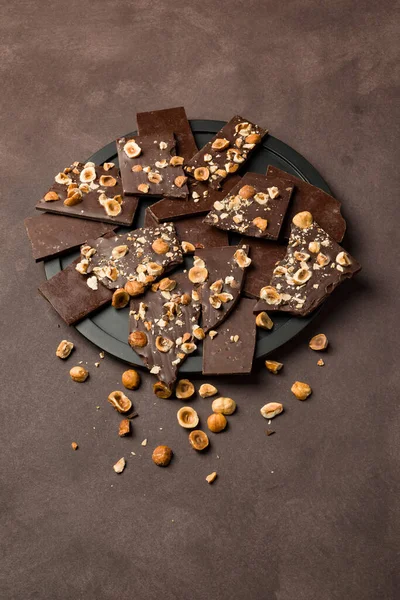 Haselnuss Dunkle Schokoladenstücke Auf Schwarzem Teller — Stockfoto