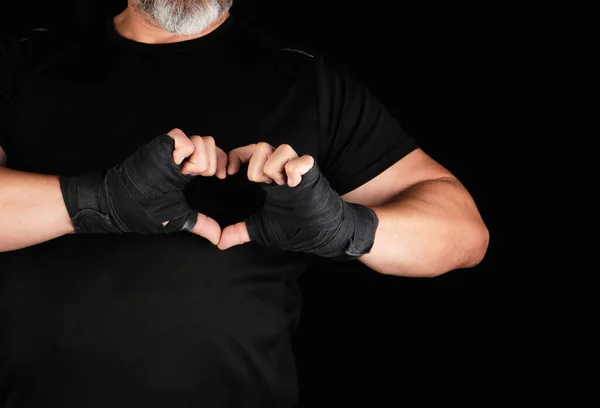 アスリートは心のシンボルを示し 男の手のひらは黒いスポーツ包帯 黒い背景に包まれています — ストック写真