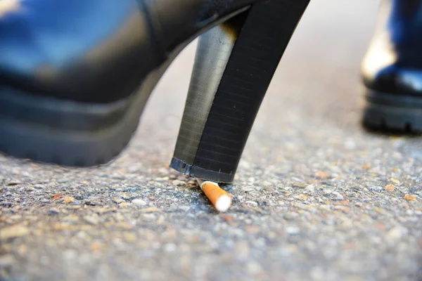 Frau Löscht Zigarette Mit Einem Schuh lizenzfreie Stockbilder