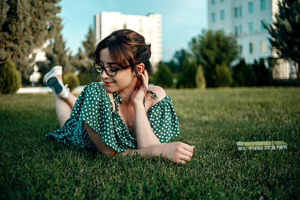 年轻的身着复古服装的高加索女孩日落时在草坪上看书 — 图库照片