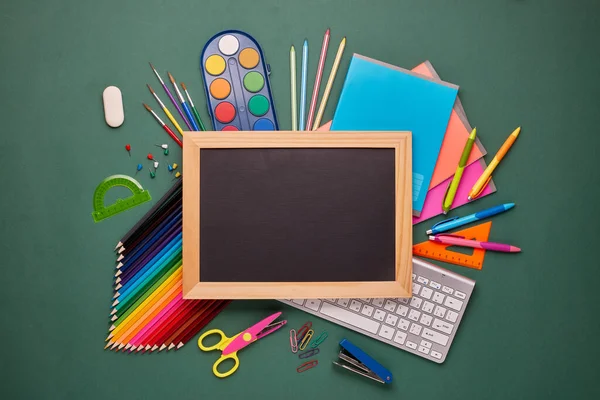 空白の黒板 コンピュータのキーボード 文房具アクセサリー 緑の背景に他のオフィス用品 トップビュー コピースペース 教育開発のための学校の付属品 — ストック写真