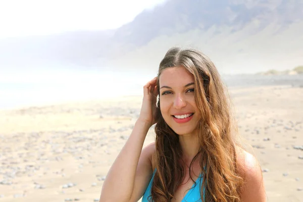 一个满头长发的微笑女孩看着外面的相机 在兰萨罗特Caleta Famara海滩度过暑假的年轻女子 — 图库照片
