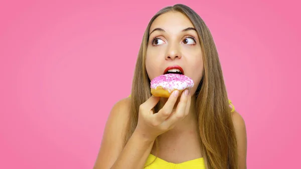 Hungrige Junge Mädchen Essen Donut Über Rosa Hintergrund Schaut Auf — Stockfoto