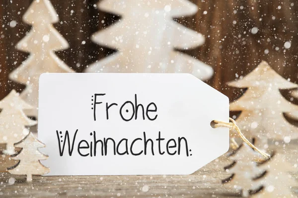 ドイツ語のテキストを持つ1つのラベルFrohe Weihnachtenはメリークリスマスを意味します 装飾として白い木製のクリスマスツリー 雪の茶色の木の背景 — ストック写真