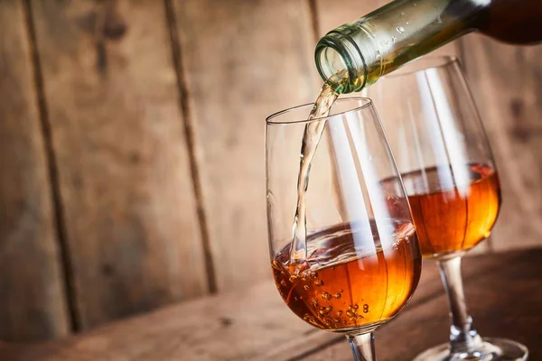 来自西班牙安达卢西亚的富丽堂皇的金色雪利酒被倒入一个时尚的葡萄酒杯中 紧靠着瓶子的脖子 在木头上有一个复制的空间 — 图库照片