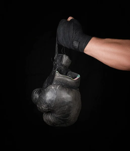 男子手臂包裹在黑色弹性运动绷带中 手持一双老式皮制拳击手套 黑色背景 — 图库照片