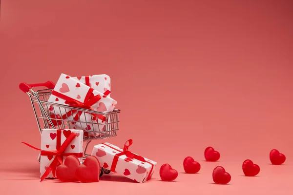 コピースペース付きのピンクの背景にギフトボックスと赤の心を持つショッピングトロリー 装飾的な心を持つお祭りの背景 結婚式日 — ストック写真