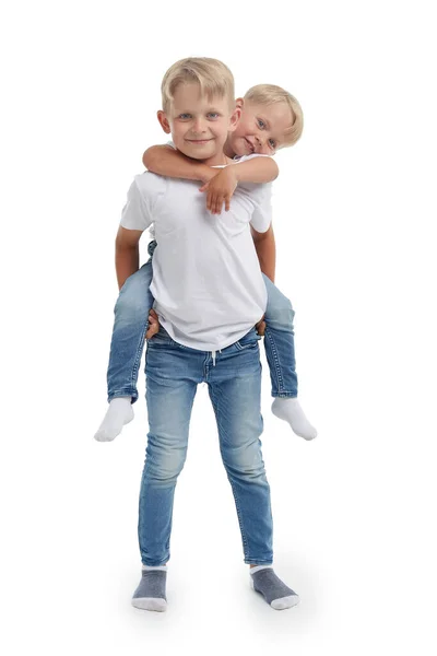 友好的家庭 哥哥抱在后面的小男孩 孤零零地站在一个白色的背景 快乐的兄弟姐妹 两个弟弟 人和家庭的概念 — 图库照片